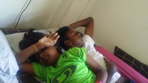 Kids in bed, eyes shut against the sunlight.